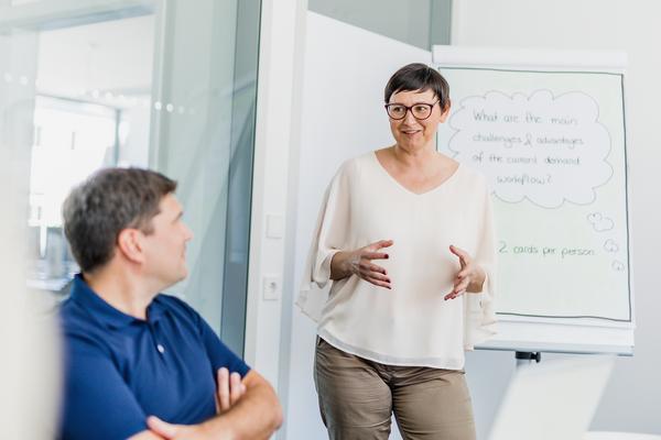 female Consultant in meeting room in front of a flipchart explaining something to her client